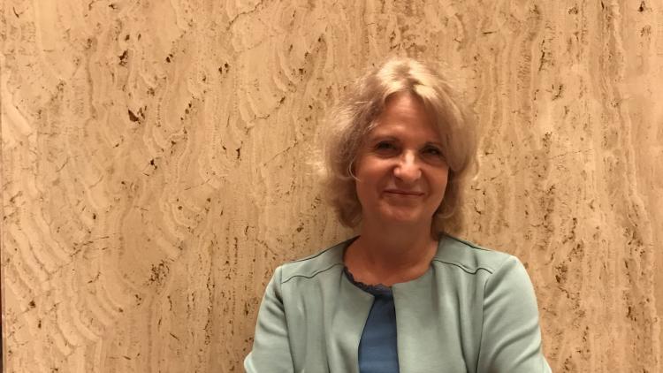 Renate Behrens smiling at the camera, in front of a marble wall.