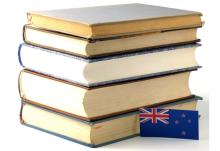 A Stack of books alsonside a tiny New Zealand flag